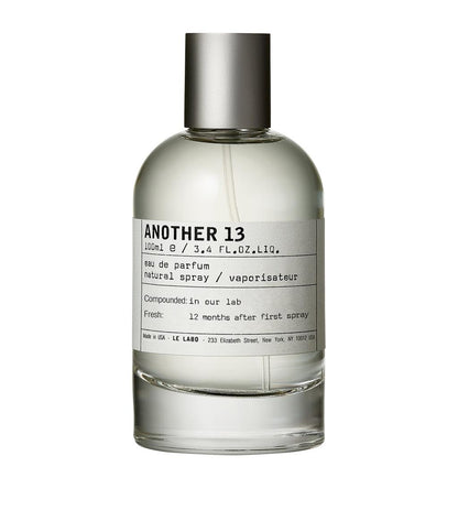 A 100ml bottle of ANOTHER 13 Eau de Parfum with a clear glass body, light-colored liquid, a white label with black text, and a metallic silver cap, shown on a plain white background.
