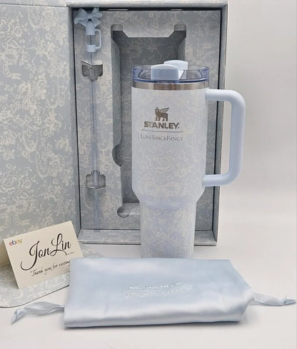 A Stanley LifetimeFangery insulated tumbler in a pale icy blue color, shown with its matching gift box, a light blue drawstring pouch, and a JonLin thank you card on a white background.
