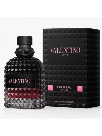 Valentino Uomo Born in Roma Intense Eau de Parfum Intense bottle with a textured black cap and base, showing a deep red liquid inside, next to its black geometric packaging box with pink lettering.